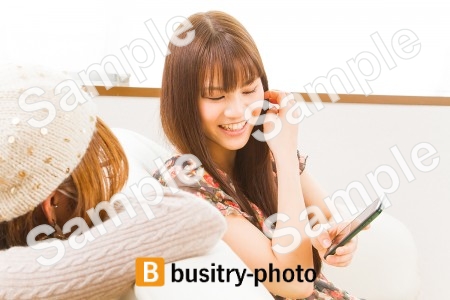 友人にスマホを見せる女性