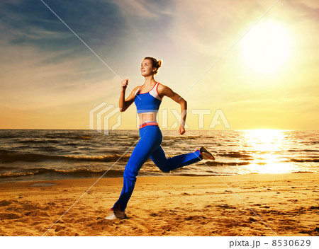 Beautiful young woman running on a beach at sunset 8530629