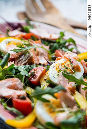 salad with salmon and verdure in pink plate on retro newspaper b 9901653