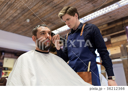 man and barber with trimmer cutting hair at salon 36212366