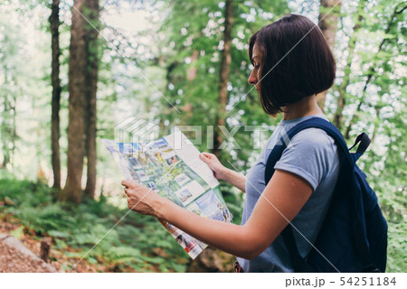 Hiker using a map to locate the destination in forest 54251184