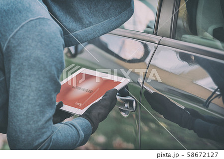 Hooded thief tries to break the car's security 58672127