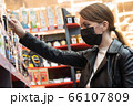 ortrait young caucasian girl in a medical black mask chooses clothes, shoes products in the supermarket. The concept of social distance and 66107809