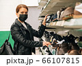 ortrait young caucasian girl in a medical black mask chooses clothes, shoes products in the supermarket. The concept of social distance and 66107815