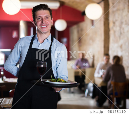 Portrait of smiling waiter with serving tray in cafe 68123110