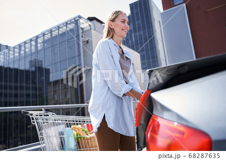 Happy young woman driving car to supermarket 68287635