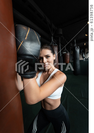 Boxing woman posing with punching bag, on dark background. Strong and independent woman concept 61398756