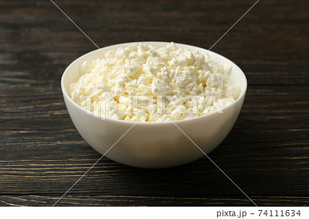 Bowl with fresh cottage cheese on wooden background 74111634