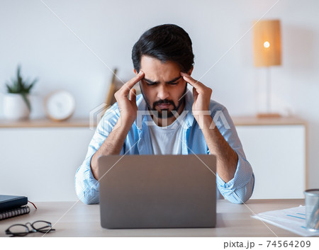 Stressed Eastern Businessman Suffering From Headache Or Business Problems At Workplace 74564209