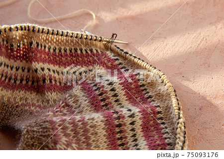 fragment of warm striped raglan sweater on pink concrete background. 75093176