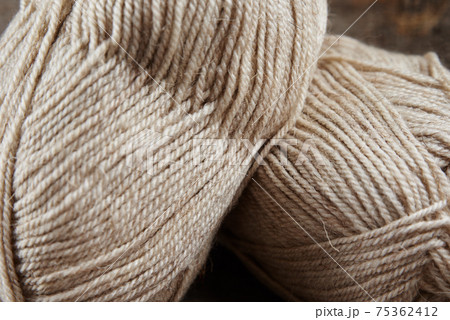 Two skeins of woolen yarn and needles for knitting on a wooden background 75362412