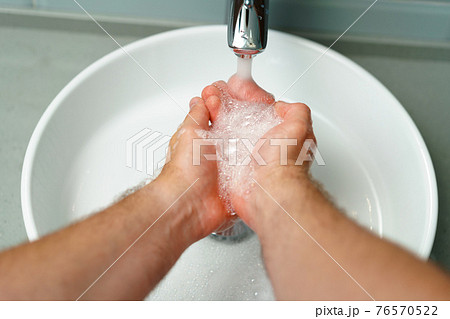 Close up photo of male hands washing with soap above the sink 76570522