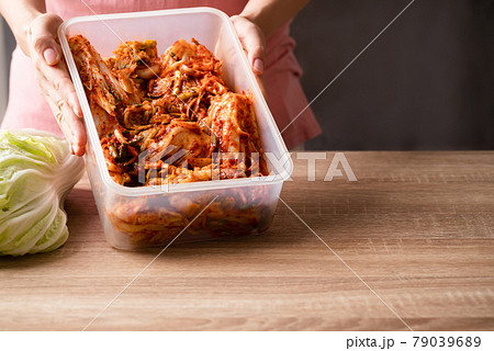 Kimchi cabbage in food container holding by hand, Popular homemade Korean food 79039689