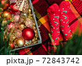 Christmas mood: wooden box with Xmas decoration of warm colors and feet in red socks with candy canes on checkered plaid 72843742