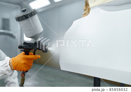 Technician in safety clothing spraying car paint 85856032