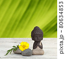 Little Buddha meditating with stones and bamboo on wooden background 80634853