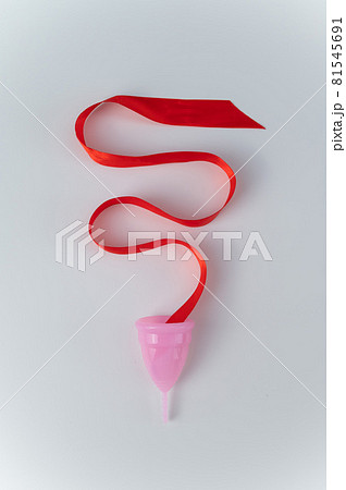 Pink menstrual cup and red satin ribbon on a white background 81545691