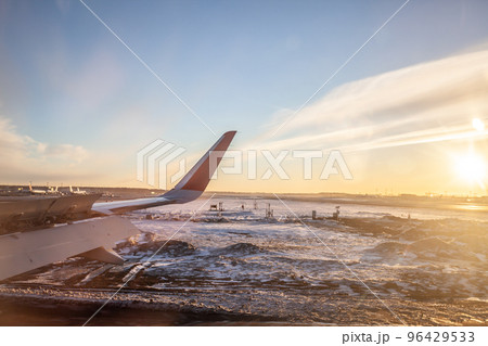 The plane is dressed for takeoff. Aircraft's wing and land seen through the illuminator. View from the window of the plane. Airplane, Aircraft. Traveling by air. Airplane flight at sunset or dawn.  96429533