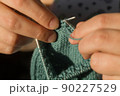 Close-up hand knitting. Hobbies, handicrafts. Knitting warm clothes from woolen fine yarn by hand on metal needles. Selective focus 90227529