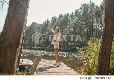 Joyous lady waving at someone from the jetty 90469732