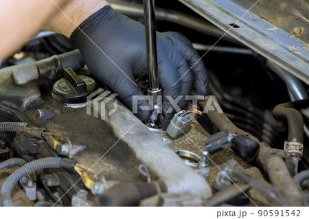 Auto mechanic makes repairs in garage service with unscrews old car candles are replaced 90591542