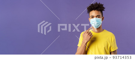 Covid19, healthcare and medicine concept. Young hispanic guy with afro haircut, wear and point at face mask, social-distancing during pandemic, explain friends how to prevent catching disease 93714353