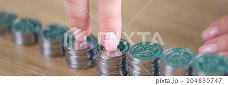 Businesswoman fingers walking on pile of coins at desk. 104830747