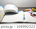 机に参考書やノートなど文房具があります。 104992322