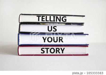 Telling us your story symbol. Books with words 'Telling us your story'. Businessman hand. Beautiful white background, copy space. Business, storytelling and telling us your story concept. 105333383