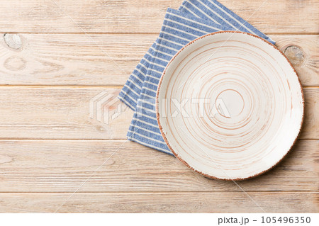 Top view on colored background empty round white plate on tablecloth for food. Empty dish on napkin with space for your design 105496350