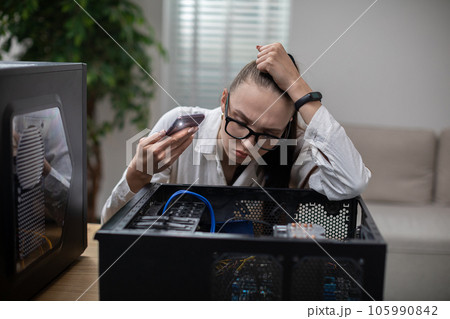 Woman shines flashlight inside broken computer 105990842