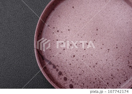 Empty round ceramic plate on a dark textured background 107742174