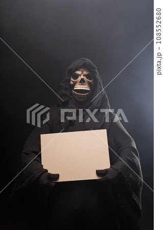 Skeleton, skull, silhouette of a man in a black robe, depicting death holding a blank poster. The 108552680