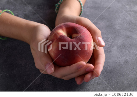 Woman's hands holding a fresh peach on dark gray background 108652136