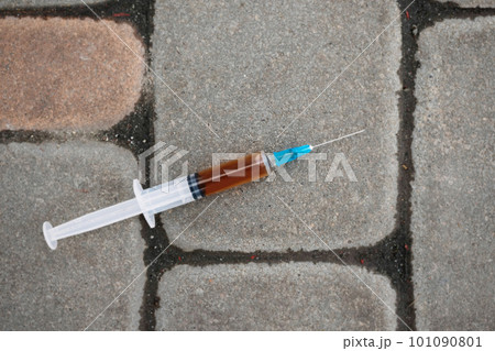 Syringe with narcotic substance on the asphalt. View from above. Addiction concept. 101090801