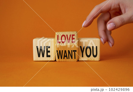 We love and want You symbol. Businessman Hand points at turned wooden cubes with words We want you and We love you. Beautiful orange background. Business and We love and want You concept. Copy space 102429896