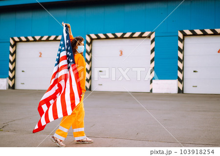 African American woman with medical face mask posing with american flag.The concept of preventing the spread of the epidemic. Covid-2019. 103918254