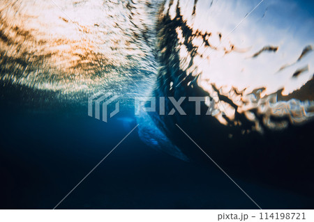 Barrel wave crashing in ocean with sunset sunlight. Underwater view of surfing wave with long shutter speed 114198721