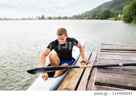 Canoeist man sitting in canoe holding paddle, getting out of water. Concept of canoeing as dynamic and adventurous sport. 114499841