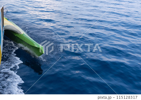 Boat outrigger cuts the blue sea surface at high speed 115128317