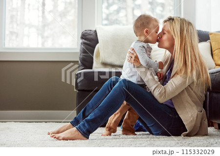 Lounge, care and kiss of baby by mom, home and bonding with son, embrace and love in apartment. House, mother and toddler in living room, hug and together on floor, happiness and wellness for boy 115332029