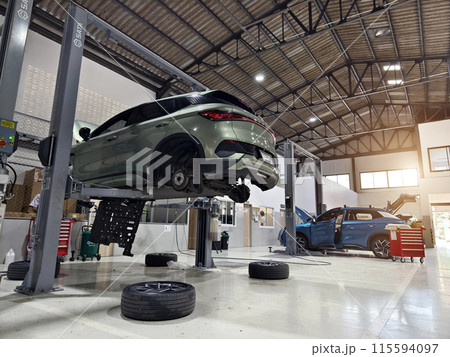 A car is raised up using a lift inside a service for maintenance 115594097