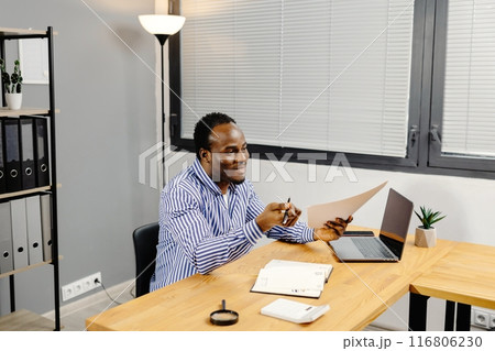 Man sitting at desk holding paper 116806230