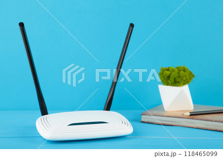 Wireless Wi-Fi router on blue background with notebook on beige 118465099