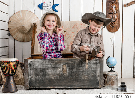 Smiling little boy and girl with jewelry while sitting in big old chest 118723555