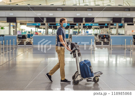 Man in mask at empty airport at check in in coronavirus quarantine isolation, returning home, flight cancellation, pandemic infection worldwide spread, travel restrictions and border shutdown 118985868