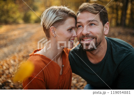 Couple in love on a walk in autumn forest. Husband and wife standing in the middle of forest, touching with foreheads. 119054881