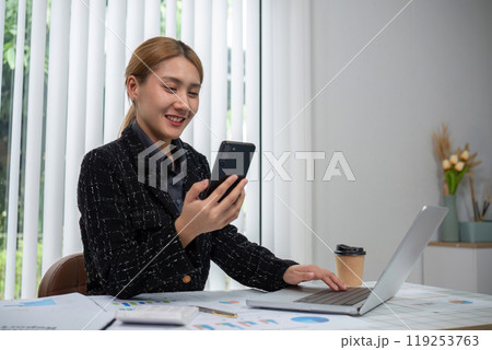 Business Woman Working on Documents at Modern Office Desk with Laptop and Smartphone 119253763