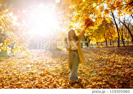 Young woman taking pictures in the autumn forest. Lady Walking In Fall Park With Yellow Foliage. 119305060