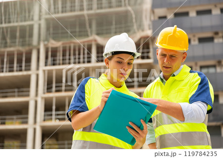 Two qualified engineers are discussing a construction plan 119784235